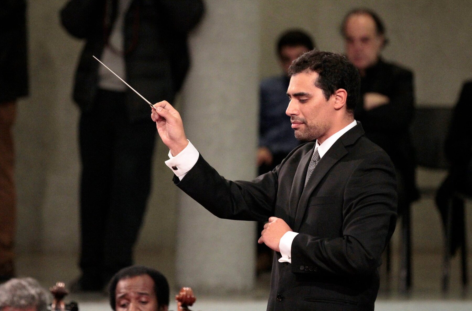 Jorge Daniel Silveyra dirigiendo con la batuta en alto, frente a la Orquesta Sinfónica Nacional de Chile
